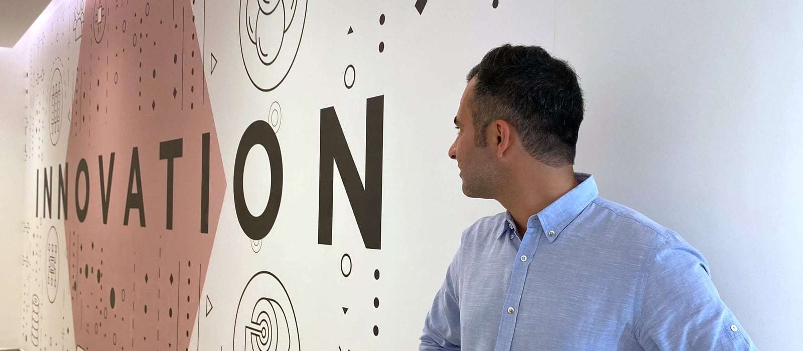 Hamed Farhadian vor einer Wand mit dem Schriftzug „Innovation“